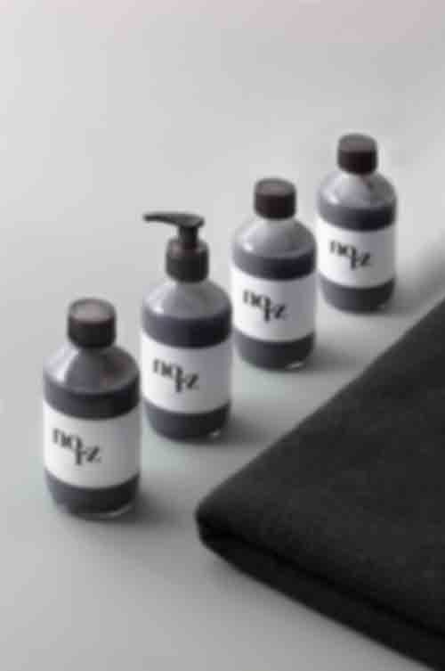 Burnt Pine Body Cleanser in Glasflaschen auf grauem Hintergrund